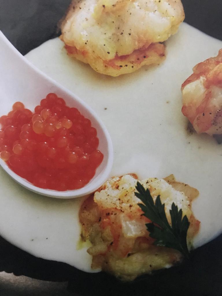 Ravioles de camarón rellenos de arroz en salsa de vino blanco y esferas de jitomate